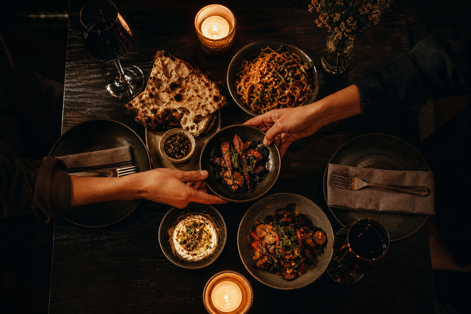 Two people sharing small plates at a candlelit table